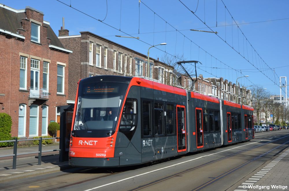Der 2015 von Siemens gebaute 'Avenio' Nummer 5028 hält am 01.05.2016 vor typisch holländischer Kulisse an der Haltestelle Stuyvesantstraat, bei dem merkwürdig anmutenden Gerüst rechts im Hintergrund handelt es sich um einen Kirchturm.