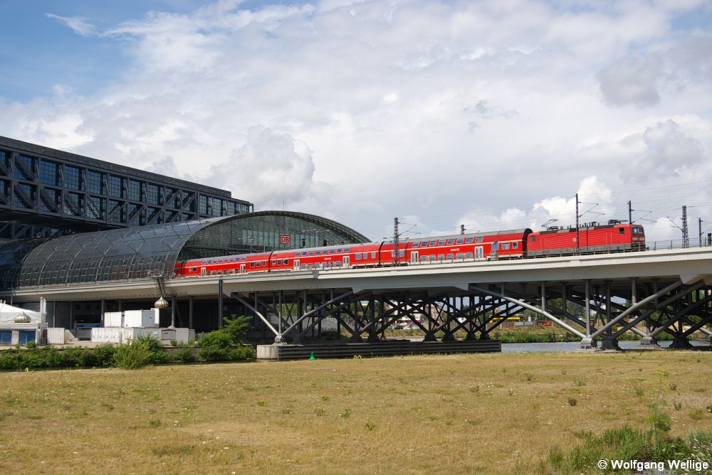 Zwei Jahre nach seiner Eröffnung war die Gegend rings um den Berliner Hauptbahnhof noch völlig unbebaut: Am 8. Juli 2008 hat Regionalexpress RE 38934 von Belzig nach Wünsdorf-Waldstadt mit einer Lok der Baureihe 143 an der Spitze gerade die Bahnhofshalle verlassen.
