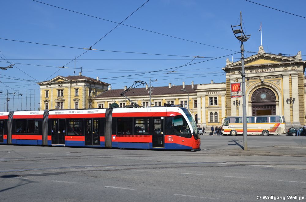 Wagen 1513 erreicht am 05.05.2014 gleich die Haltestelle Glavna železnička stanica / Главна железничка станица vor dem Hauptbahnhof, dessen Empfangsgebäude im Hintergrund zu sehen ist. Mitte 2018 wurde der Eisenbahnbetrieb hier eingestellt und ein neuer Bahnhof in Betrieb genommen, der jedoch weit außerhalb der Innenstadt liegt.