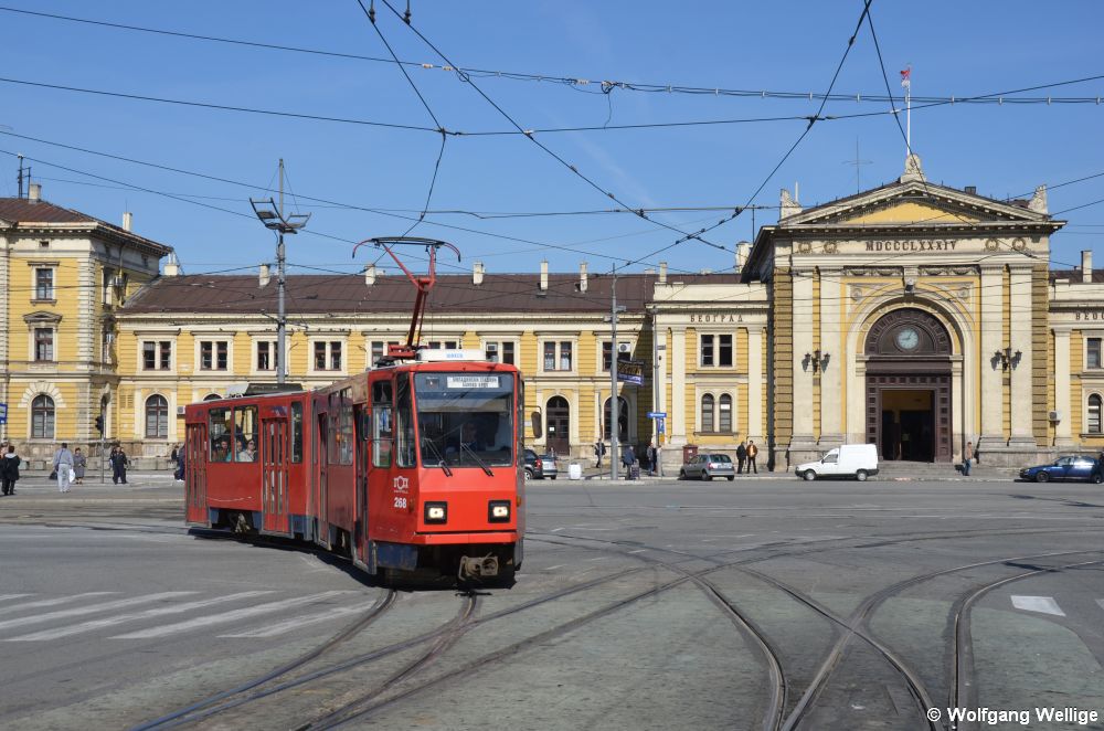 Der von CKD in Prag gebaute Tatra KT4YU Nummer 268 hat am 05.05.2014 gerade die Haltestelle Glavna železnička stanica / Главна железничка станица vor dem Hauptbahnhof verlassen, dessen Empfangsgebäude im Hintergrund zu sehen ist. Mittlerweile ist der Bahnhof außer Betrieb.