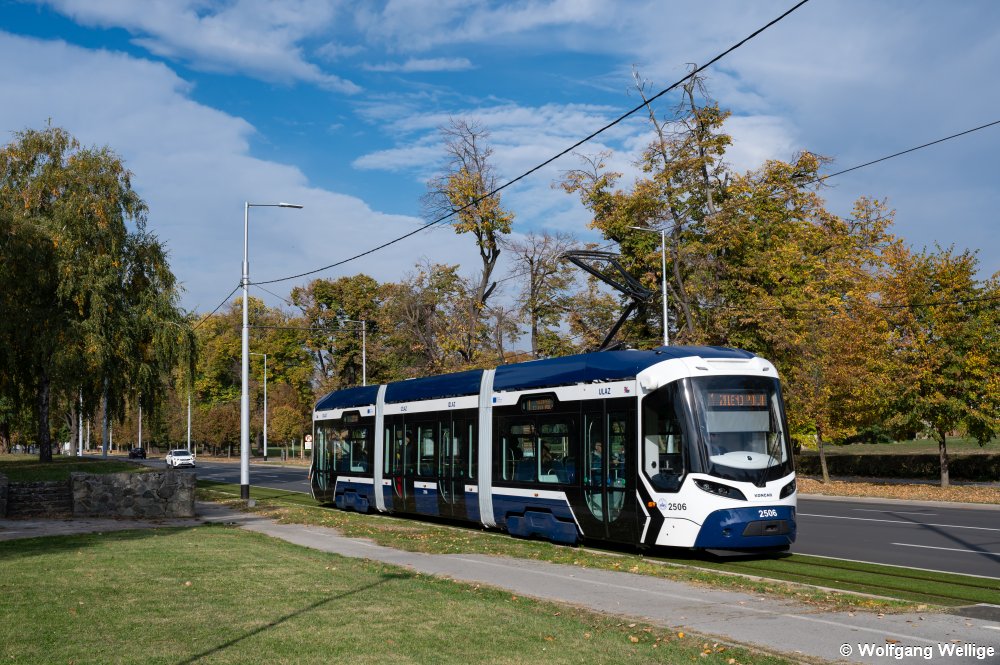 Im Frühjahr 2025 gingen die allerersten Niederflurfahrzeuge in Osijek in Betrieb. Am 20.10.2025 fährt Wagen 2506 des von Končar gebauten Typs TMK 2500 bei herrlichem Herbstwetter an einem Park vor der Haltestelle Tvrđa entlang.